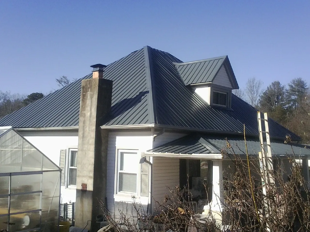 Dark blue standing seam metal roof on a white farmhouse with dormer — Slate & Tile Roof Repair by Roofing Brothers in Cumberland